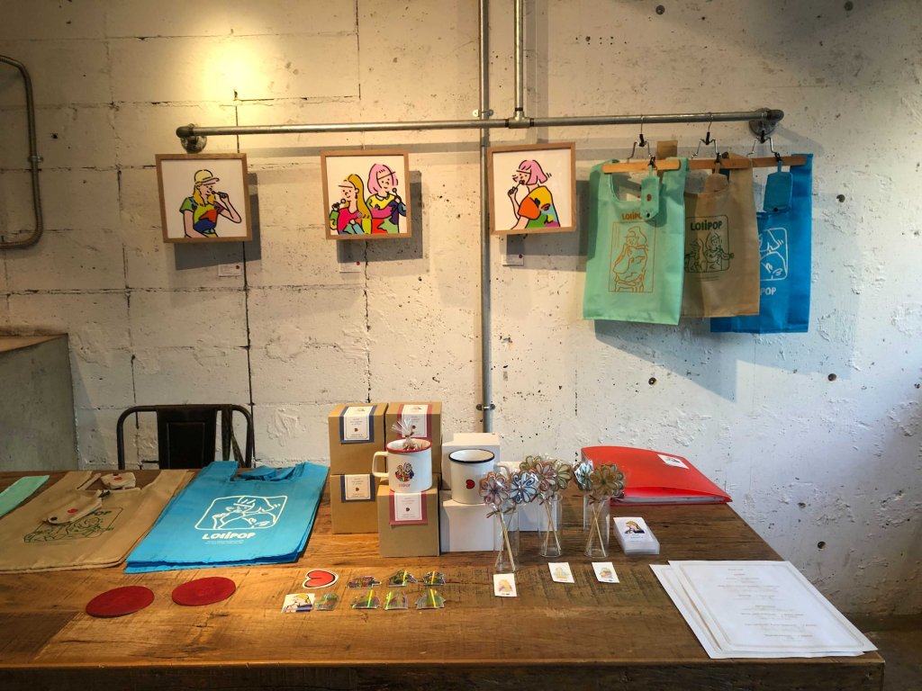 Hayata個展「LOLIPOP」グッズ販売の様子。バッグやカップなどのグッズが並ぶ。　photo by pinoko